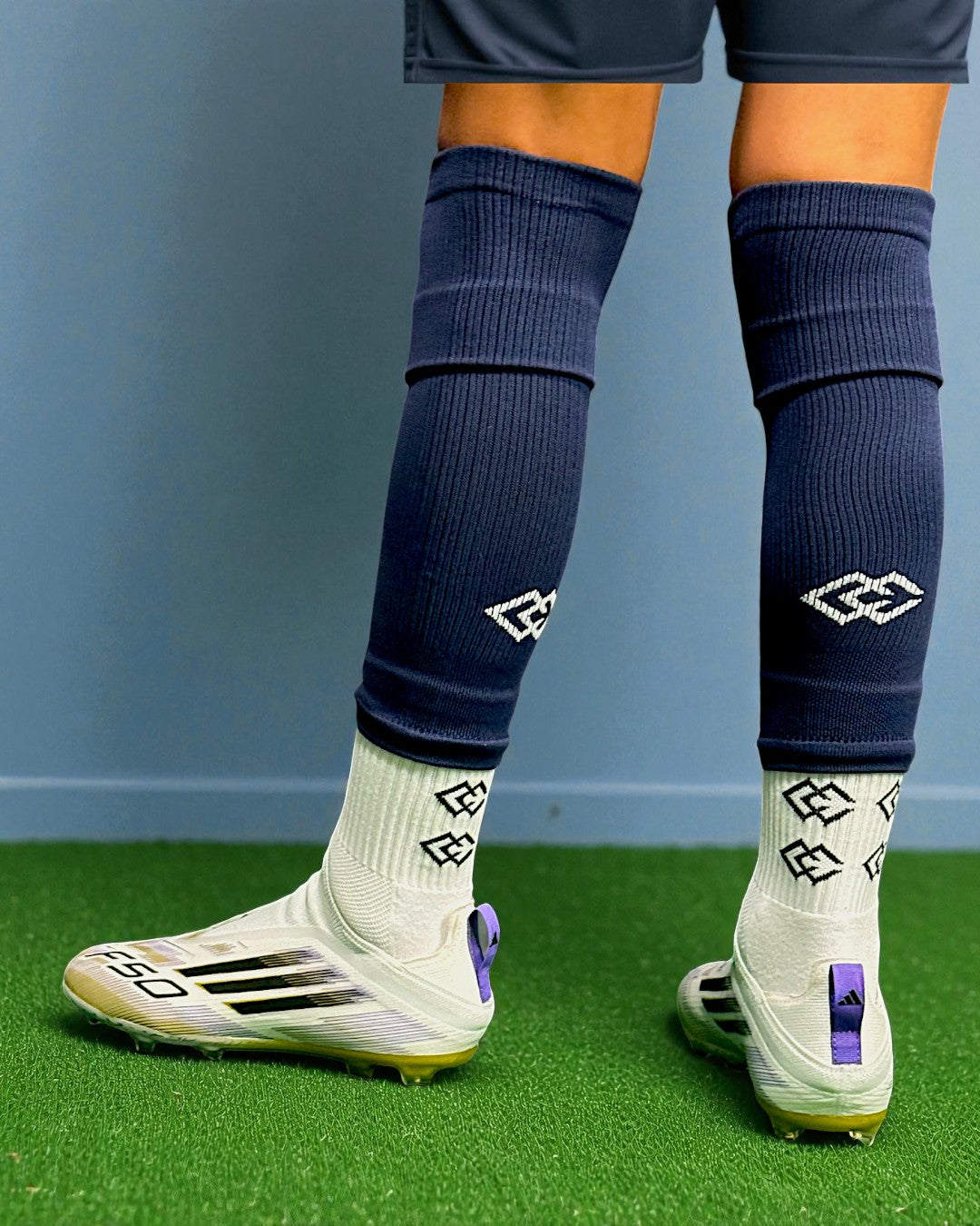 Rear view of a player wearing navy C3 pre-cut socks over white C3 grip socks on turf