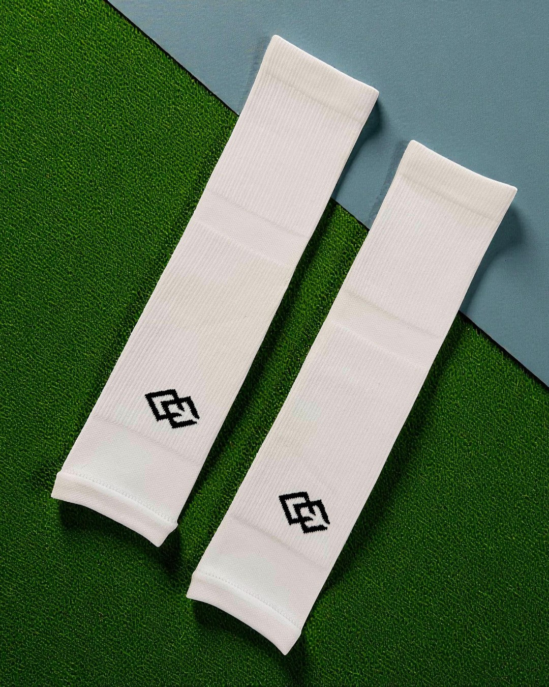 Pair of white C3 pre-cut socks with C3 logos laid flat on green turf