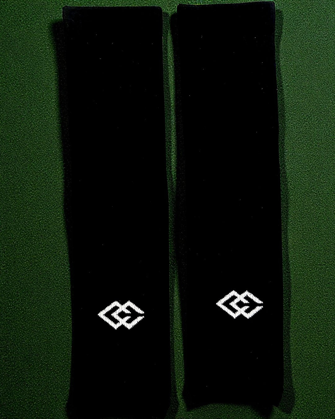 Pair of black C3 pre-cut socks with C3 logos laid flat on green turf