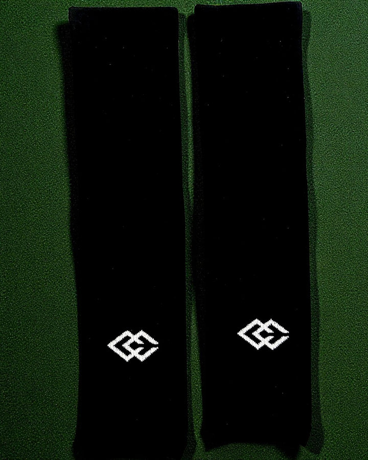 Pair of black C3 pre-cut socks with C3 logos laid flat on green turf