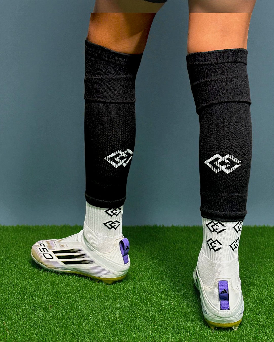 Rear view of a player wearing black C3 pre-cut socks over white C3 grip socks on turf