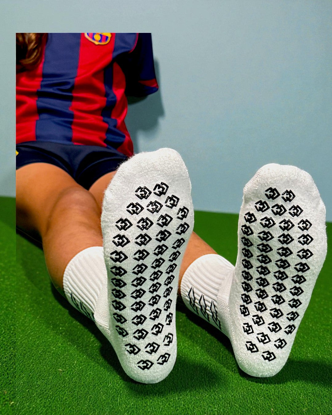 Soles of white C3 grip socks showing the black C3 logo grip pattern on turf