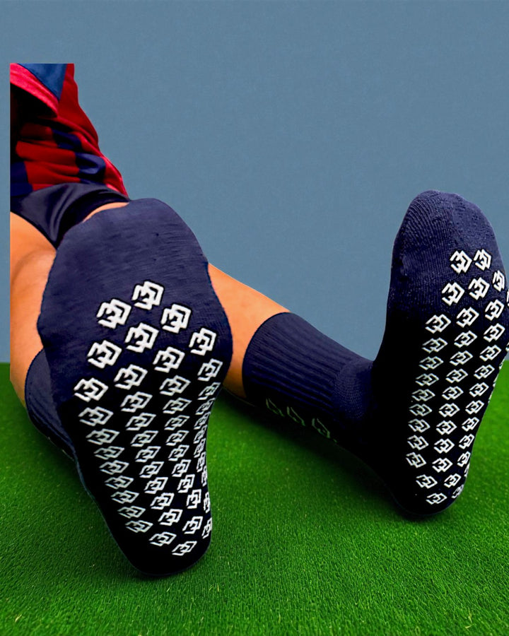 Soles of navy C3 grip socks showing the white C3 logo grip pattern on turf
