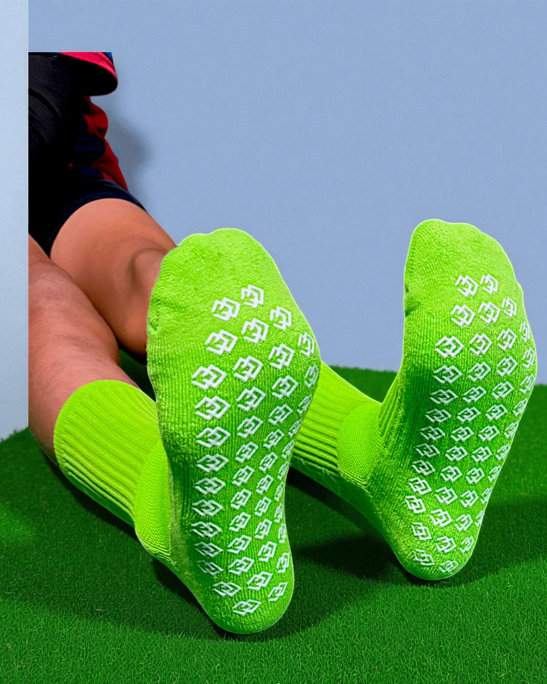 Soles of lime green C3 grip socks showing the white C3 logo grip pattern on turf