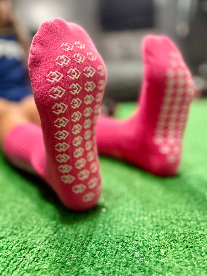 Close-up of pink C3 grip sock soles showing the white C3 logo grip pattern on turf