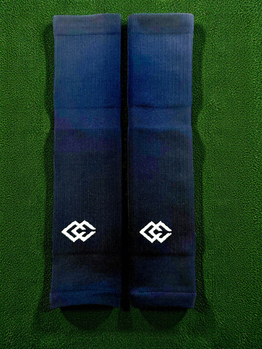 Pair of navy C3 pre-cut socks with C3 logos laid flat on green turf