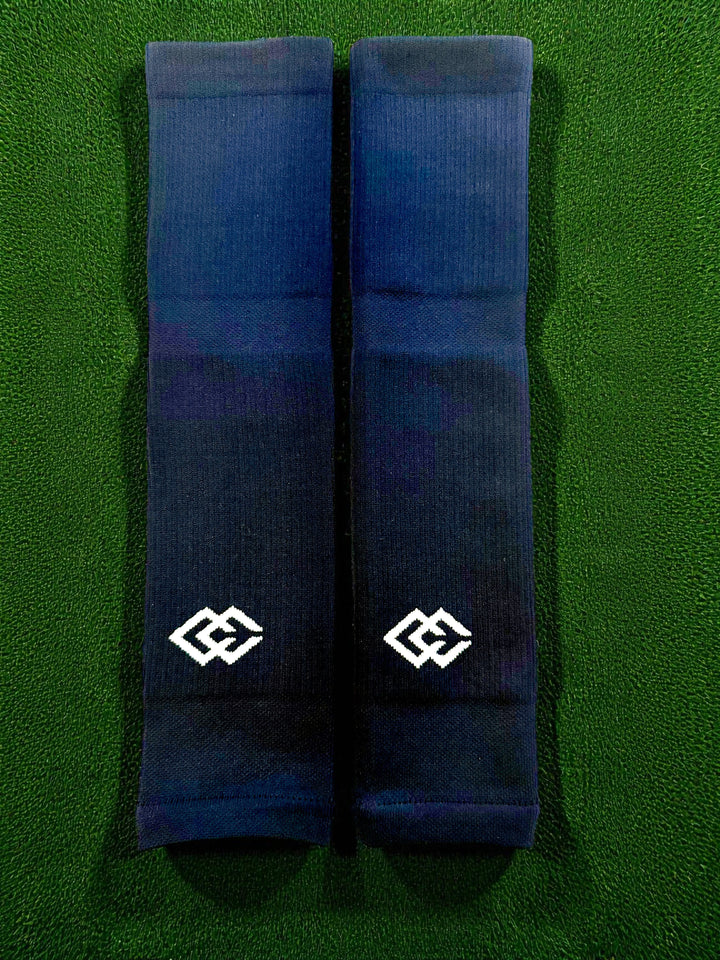 Pair of navy C3 pre-cut socks with C3 logos laid flat on green turf