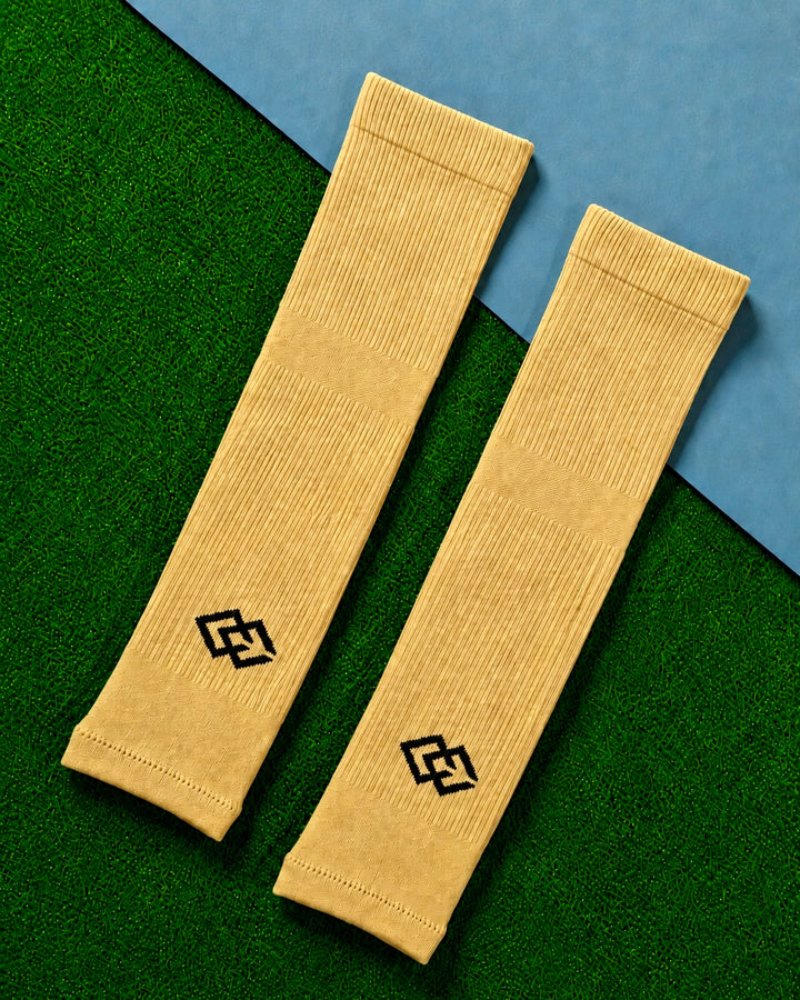 Pair of gold C3 pre-cut socks with C3 logos laid flat on green turf